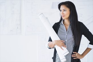 Hispanic architect carrying blueprints in office
