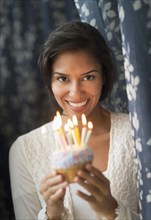 Hispanic woman holding birthday cupcake