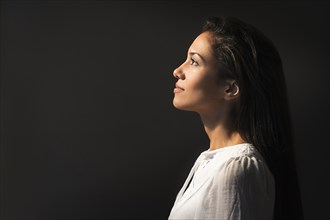 Hispanic woman looking up into light