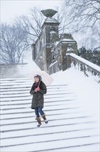 Asian woman walking on snowy steps