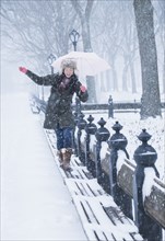 Asian woman walking on benches in snowy Central Park