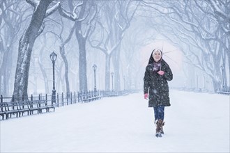 Asian woman walking in snowy Central Park