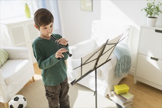 Hispanic boy practicing recorder in living room