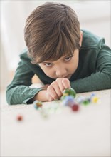 Hispanic boy playing with marbles on floor