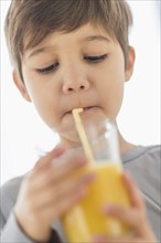 Hispanic boy drinking juice with straw