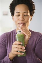 Close up of Black woman drinking green smoothie