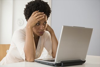 Frustrated Black businesswoman using laptop