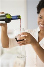 Black woman pouring glass of red wine