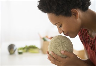 Black woman smelling cantaloupe