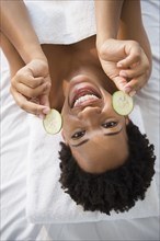Portrait of smiling Black woman holding cucumber slices
