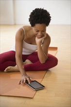 Black woman using digital tablet on yoga mat