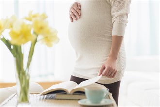 Pregnant Hispanic woman reading book