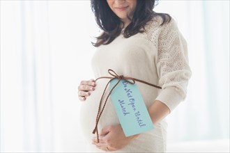 Pregnant Hispanic woman with gift wrap around belly
