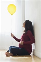 Pregnant Hispanic woman holding balloon