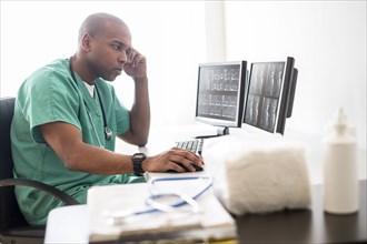 Black doctor working on computer in office