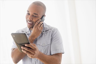 Black man using digital tablet and cell phone