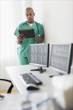 Black doctor using digital tablet in office