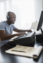 Black musician writing music on computer