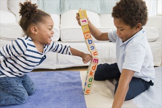 Black children playing with blocks in living room