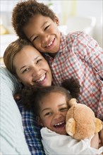 Black mother and children smiling on sofa