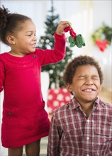 Black children playing with mistletoe in living room
