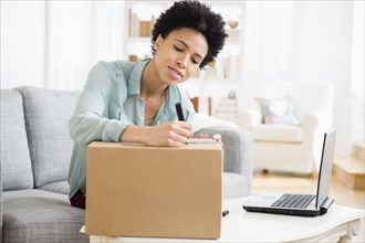 Black woman writing address on package