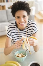 Black woman eating fruit and cereal for breakfast
