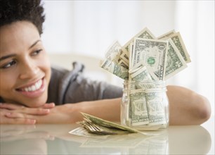 Black woman admiring saved money in jar