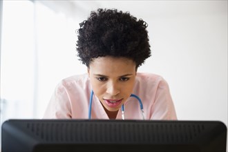 Black nurse working on computer in office