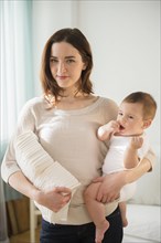 Mother holding baby and stack of diapers