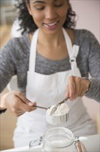 Mixed race woman measuring flour in kitchen