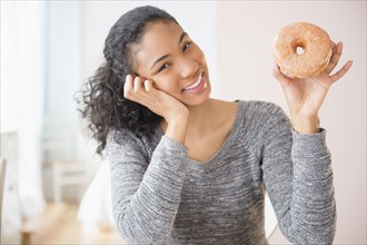 Mixed race woman holding donut
