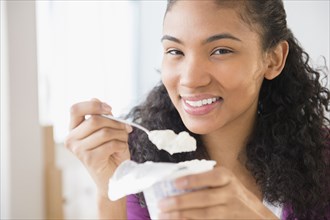 Mixed race woman eating yogurt