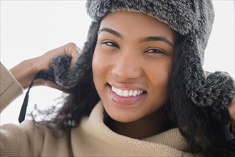 Mixed race woman wearing furry hat in snow