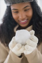 Mixed race woman holding snowball outdoors