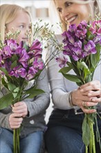Senior Caucasian woman and granddaughter holding bouquets of flowers