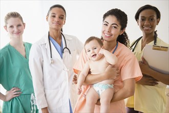Nurses and doctor smiling with baby