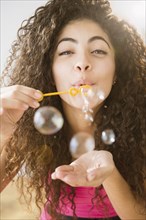 Mixed race woman blowing bubbles