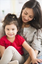 Hispanic mother and daughter sitting together