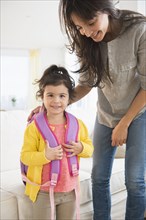 Hispanic mother getting daughter ready for school