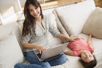 Hispanic mother and daughter relaxing on sofa