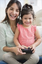 Hispanic mother and daughter playing video games together