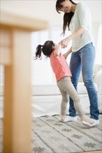 Hispanic mother and daughter dancing together