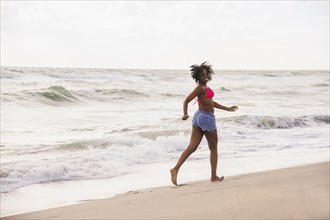African American woman walking on beach