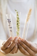 Mixed race woman holding test tubes of herbs