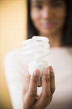 Mixed race woman holding light bulb