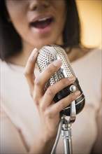 Mixed race woman singing into vintage microphone