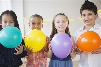 Children holding colorful balloons at party