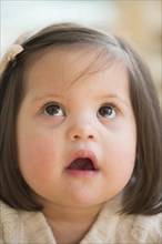 Hispanic toddler with Down syndrome looking up