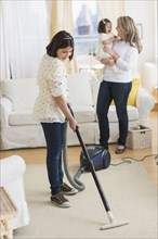 Hispanic girl vacuuming living room